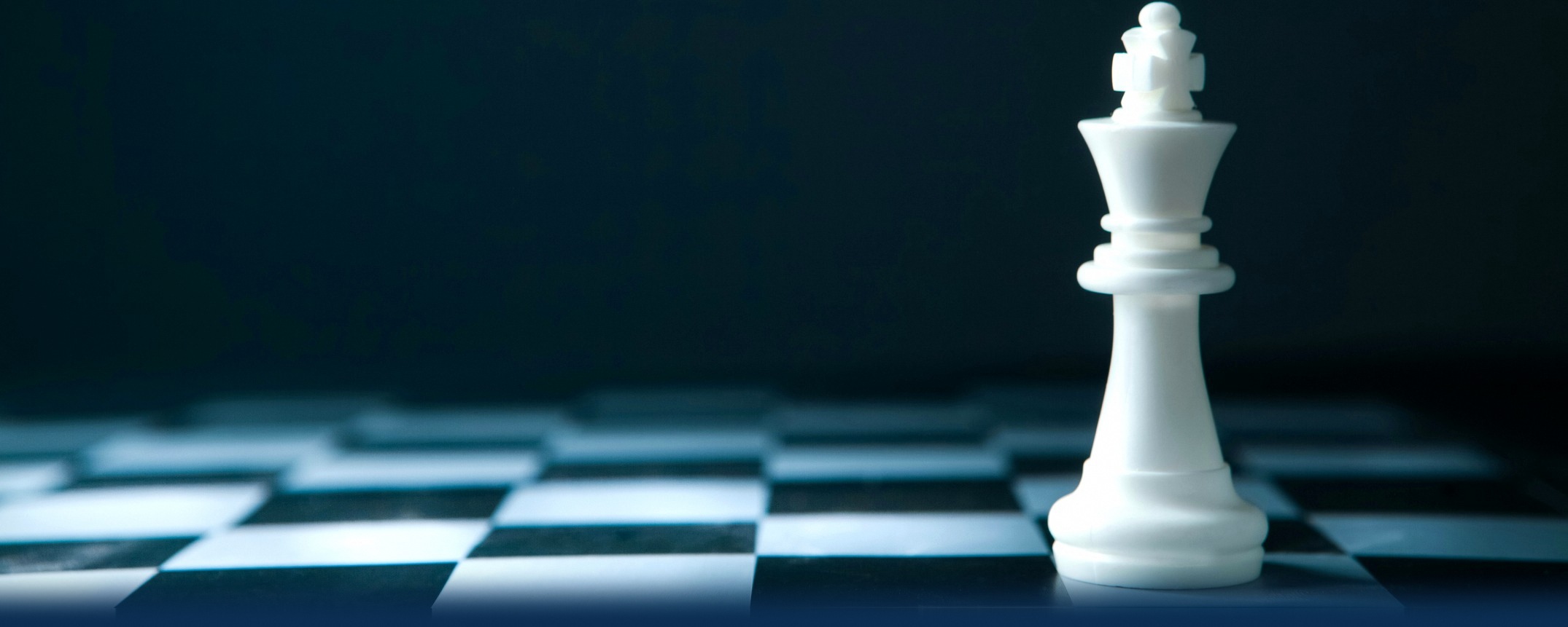 A white chess king standing on a chessboard against a dark background